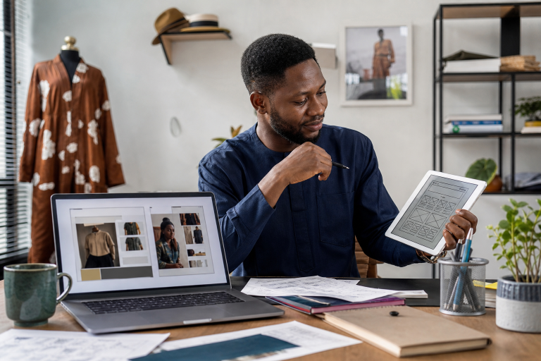 Nigerian SME founder comparing website builder and custom design options on a laptop in a modern office